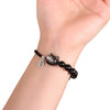 Close-up of a wrist wearing a black obsidian bracelet with a small cat charm and silver tag