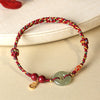 Close up of a braided bracelet with a jade donut bead and gold charm