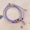 Triple wrap bracelet with purple beads and gold star charm on a white dish