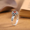 Close-up view of a zinc alloy adjustable ring with a red stone set inside a lotus flower top.