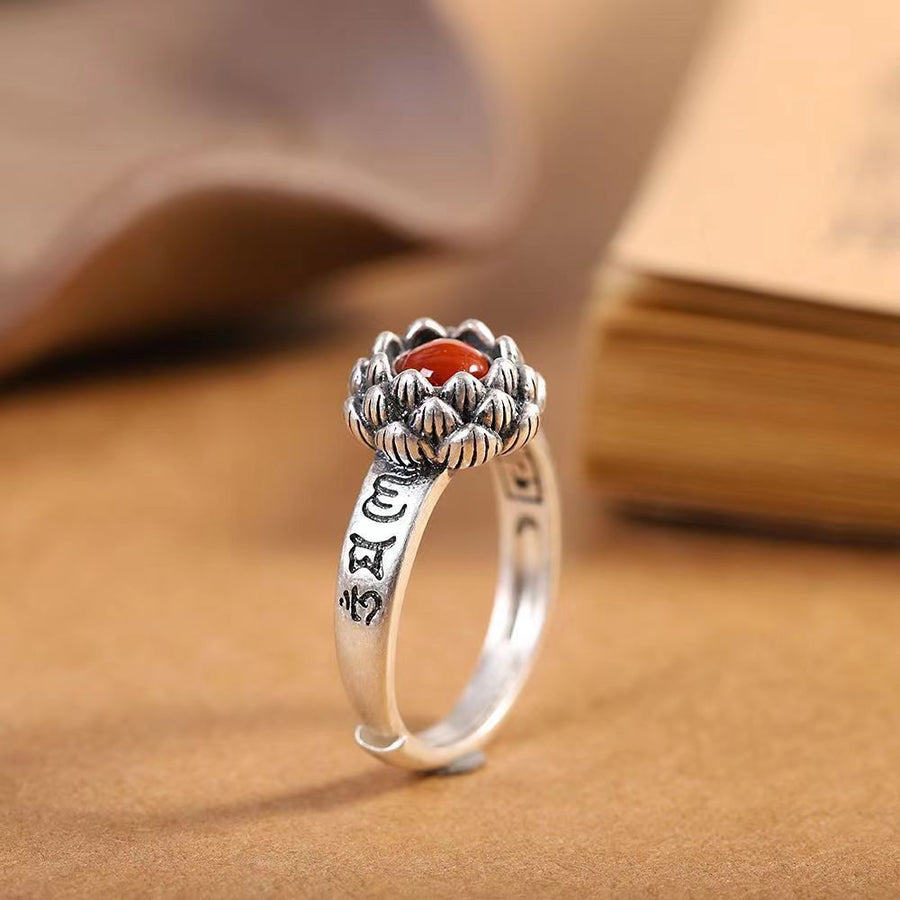 Close-up view of a zinc alloy adjustable ring with a red stone set inside a lotus flower top.