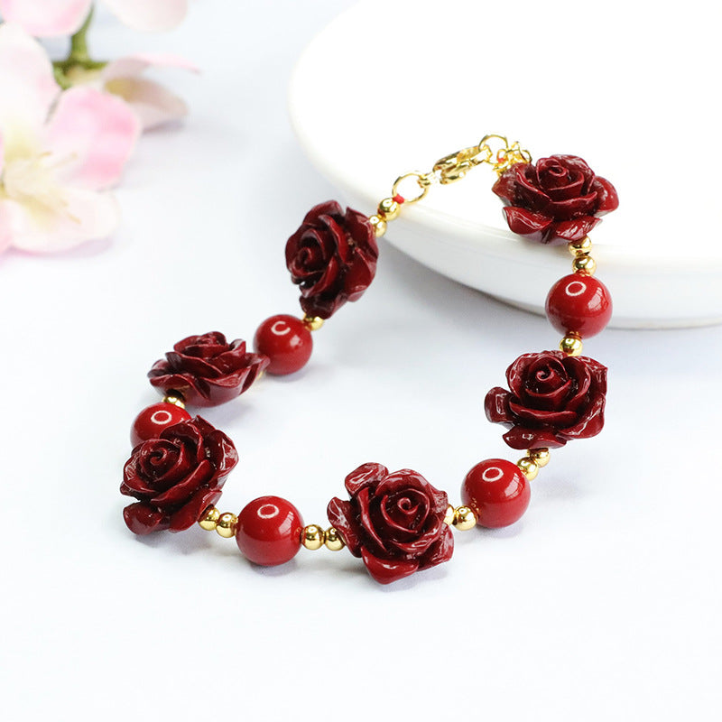 Red cinnabar bracelet with carved rose charms and gold-tone chain clasp on a white surface