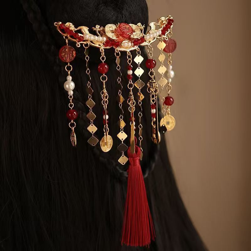 Gold-tone hair comb with red beads, pearls, and a long red tassel worn in dark hair