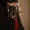 Gold-tone hair comb with red beads, pearls, and a long red tassel worn in dark hair
