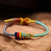 Close-up of a colorful woven cord bracelet with a gold-tone knot on a wooden surface