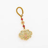 Hand holding a car key with a gold-tone enamel lock charm hanging from it