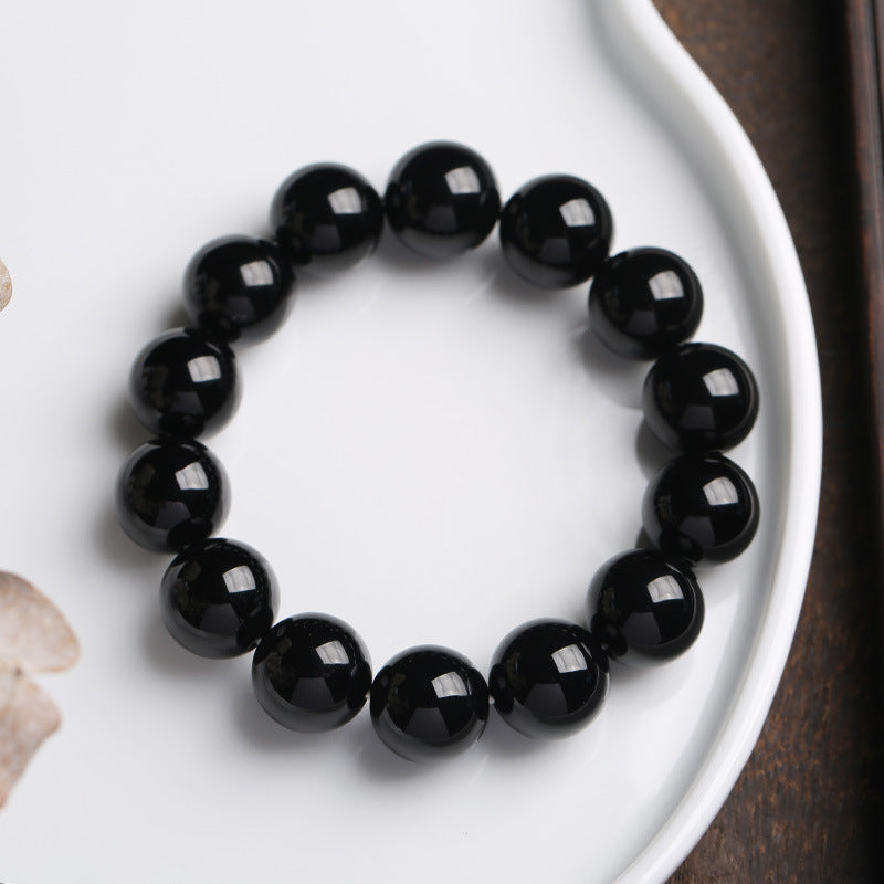 Faceted natural black onyx bracelet resting on a white ceramic dish
