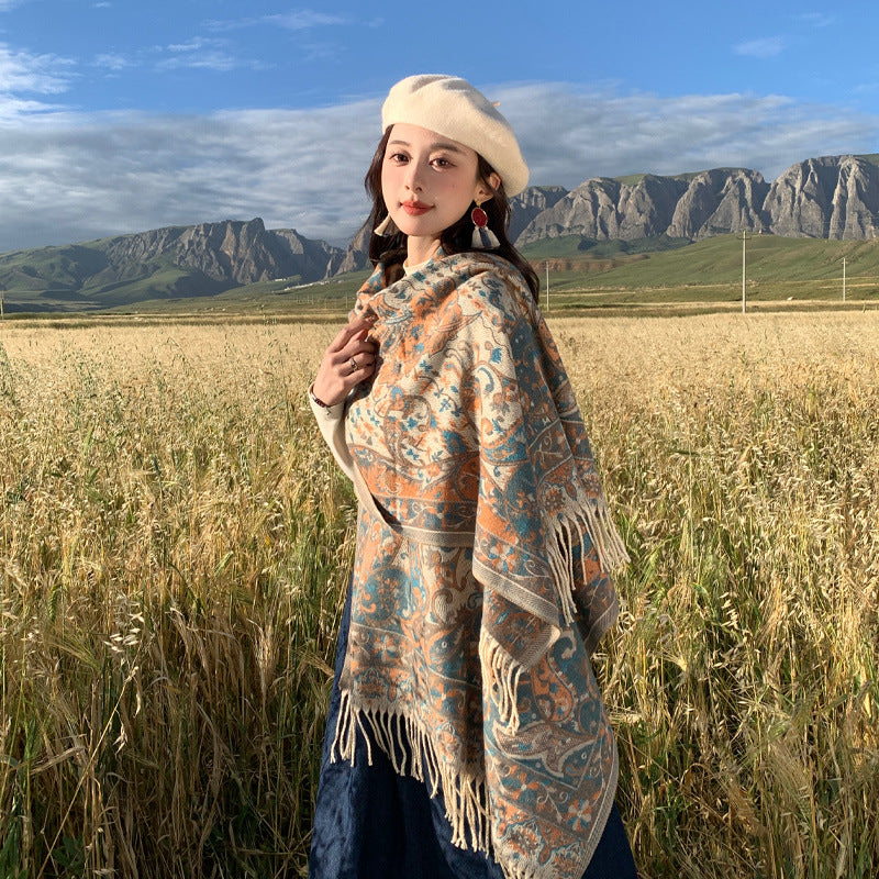 Woman wearing a beige Tibetan style shawl with tassels in a field