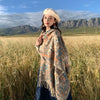 Woman wearing a beige Tibetan style shawl with tassels in a field