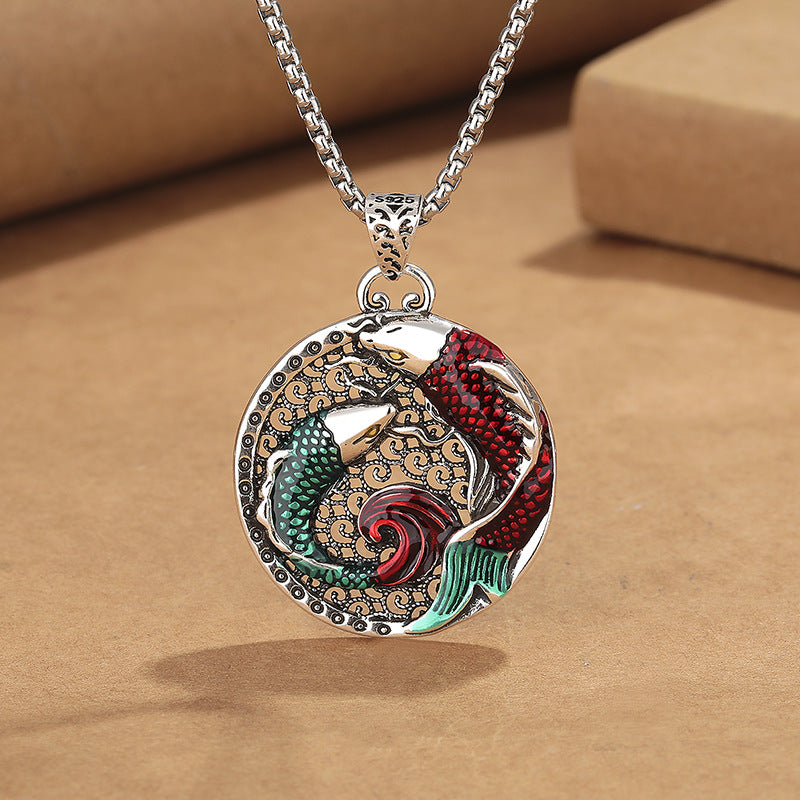 Close up of a copper necklace pendant with red and green enamel koi fish