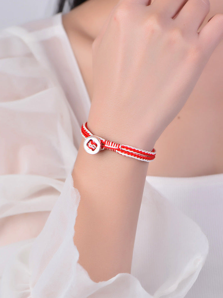 Close up of red and white woven bracelet with silver button clasp on wrist