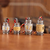 Four cylindrical pendants with Tibetan script sitting on a wooden surface