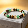 A close-up of a beaded bracelet with tiger eye and citrine stones on a grey box.