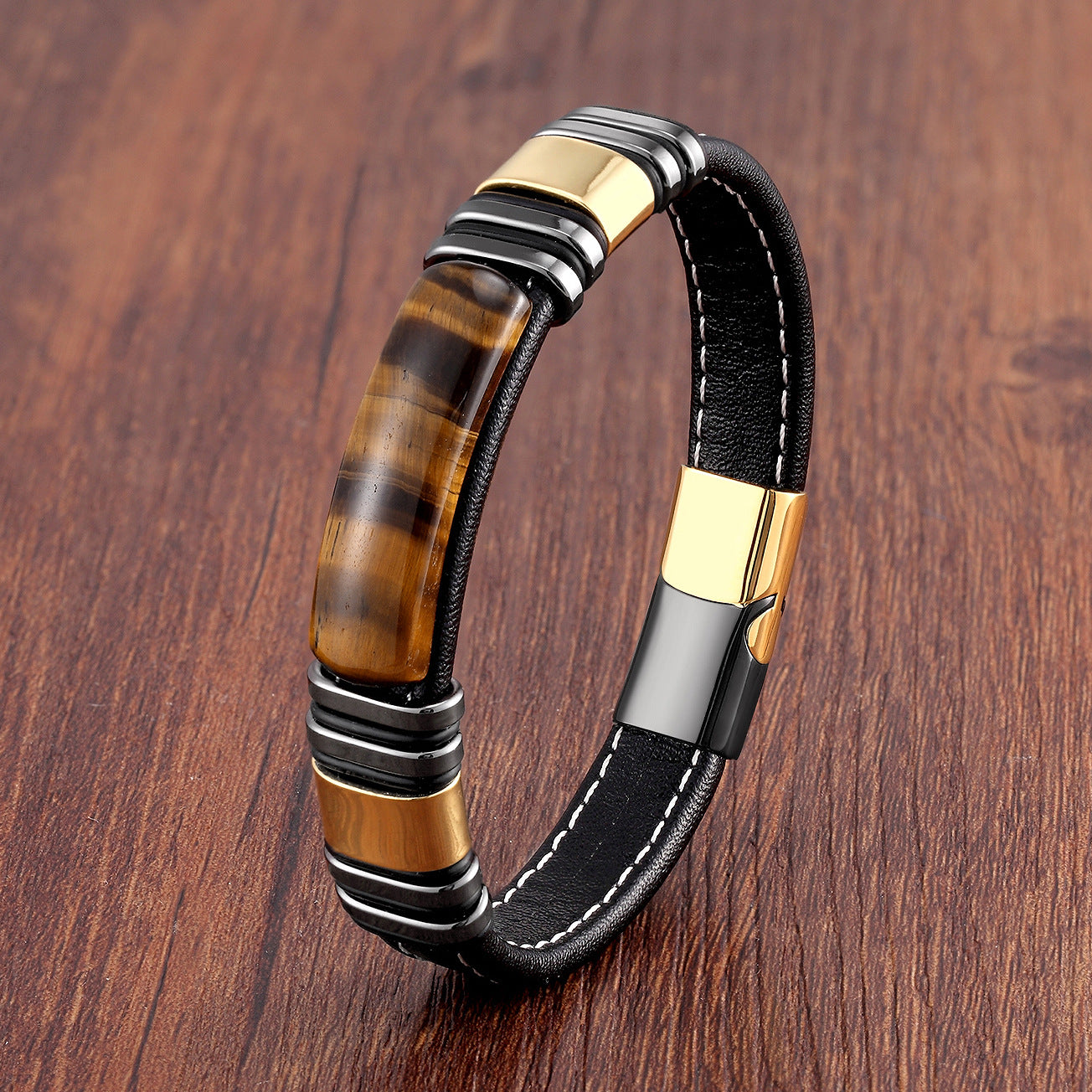 Close-up of a Tiger Eye stone leather bracelet with a gold-tone metal clasp on a wooden surface