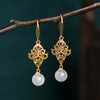 Pair of gold tone dangle earrings with white chalcedony beads hanging from a branch