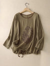 Olive green cotton linen top with tree embroidery hanging on a wooden hanger