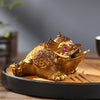 Gold-colored resin tea pet figurine shaped like a mythical toad sitting on a tea tray