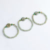 Three jade bead bracelets with peace buckles arranged on a white background