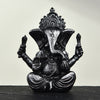 Small resin Ganesha statue sitting on a dark surface