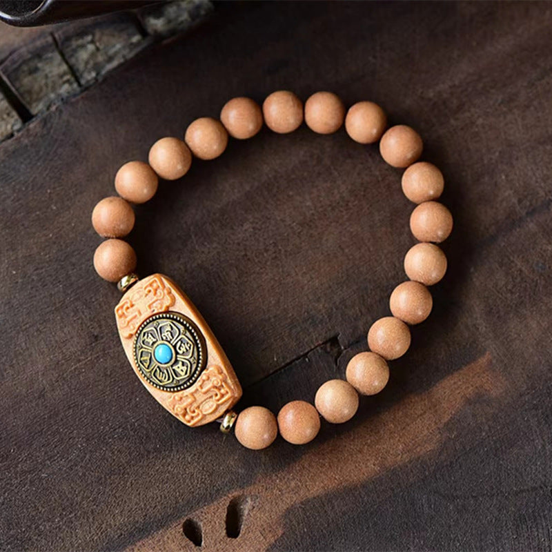 Close up of a wooden bead bracelet with a rotating carved barrel charm