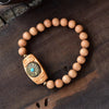 Close up of a wooden bead bracelet with a rotating carved barrel charm