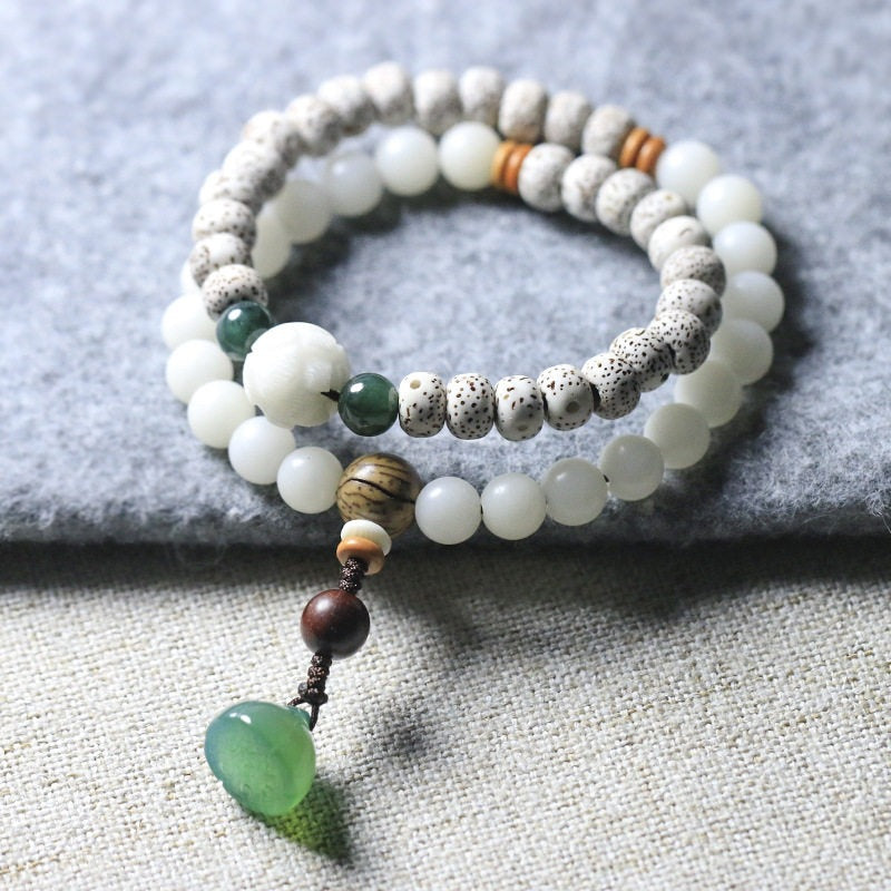Double wrap bracelet with speckled bodhi seeds and white beads resting on grey fabric