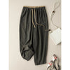 Flat lay of dark green cotton linen wide leg pants with drawstring waist next to a white bag