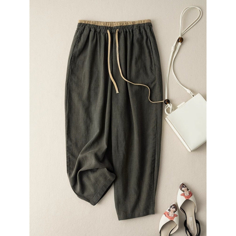 Flat lay of dark green cotton linen wide leg pants with drawstring waist next to a white bag