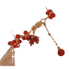 Close up of a red agate bracelet with a gold maple leaf charm on a wrist