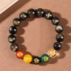 Close up of an obsidian beaded bracelet with five colorful wealth god charms