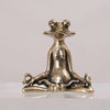 Close up of a small brass frog sitting in a yoga pose on a wooden table