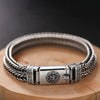 Silver braided bracelet with mantra engraving on wooden surface