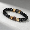 Close-up of a beaded bracelet with black and brown faceted stones on a light background