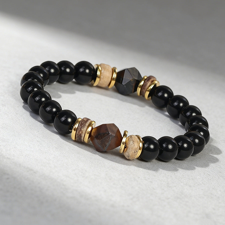 Close-up of a beaded bracelet with black and brown faceted stones on a light background