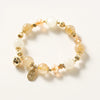 Close up of a beaded bracelet with golden rutilated quartz and white stones on a white background
