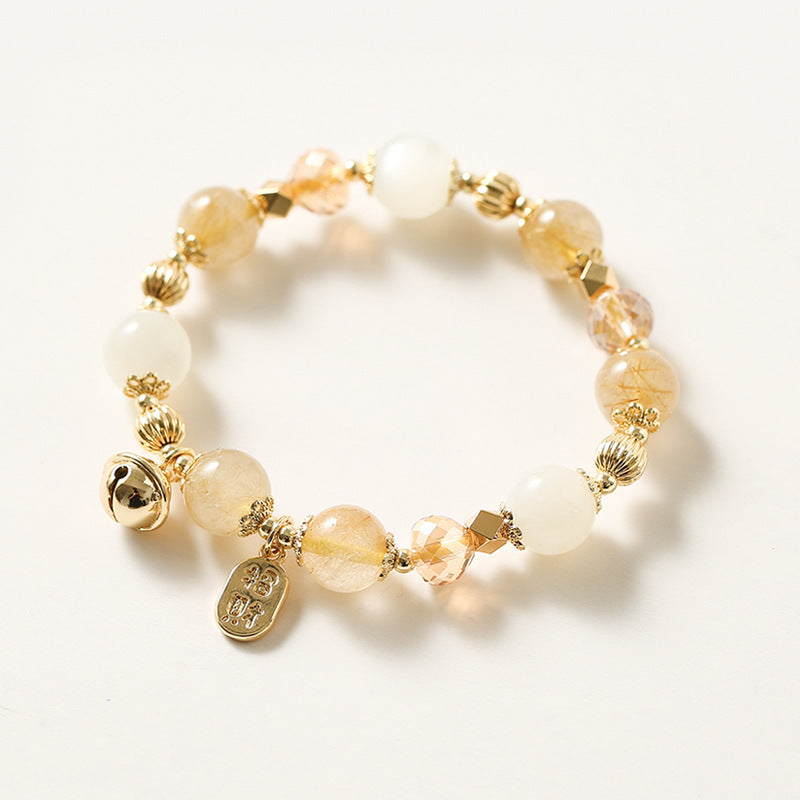 Close up of a beaded bracelet with golden rutilated quartz and white stones on a white background