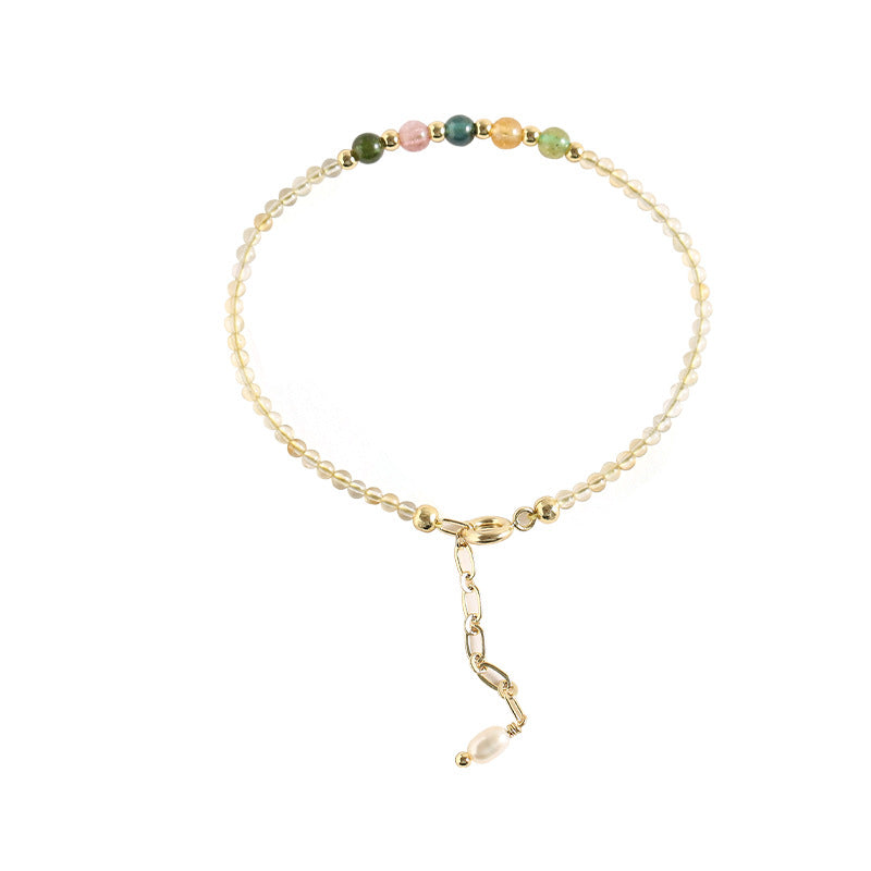 Close up of a thin yellow citrine beaded bracelet with gold clasp on white background