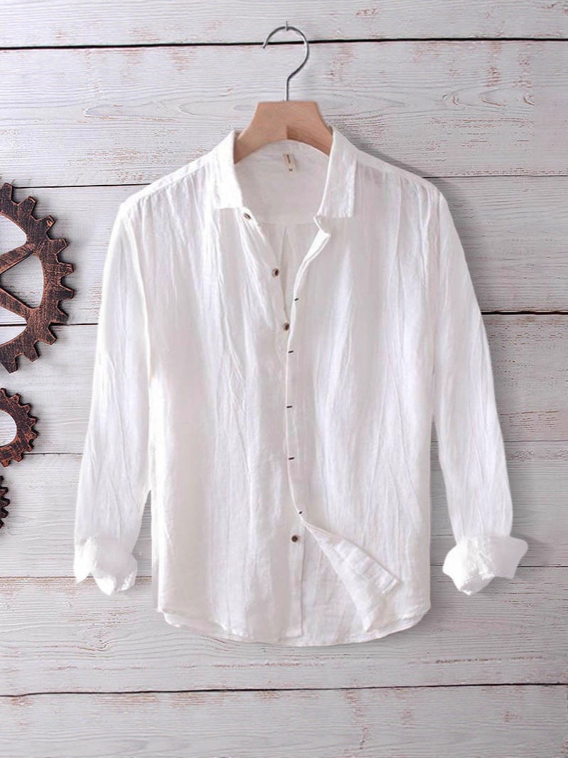 White men's long sleeve cotton linen shirt hanging on a wooden hanger against a white wood background