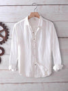 White men's long sleeve cotton linen shirt hanging on a wooden hanger against a white wood background