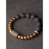 A bracelet with black stones and gold metal beads on a dark background