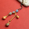 Close-up of a handmade wooden key chain with three charms and beads on a red background