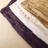 Three folded midi skirts in purple, white, and beige showing embroidery details