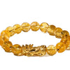 Close-up of a yellow beaded bracelet with a gold Pixiu charm on a white surface