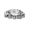 Close-up of a silver-tone metal bracelet with two leopard head charms and leaf-shaped links on a wooden surface