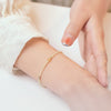 Close up of a wrist wearing a thin yellow citrine beaded bracelet with gold hardware