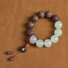Close-up of a brown wood bead bracelet with carved patterns and light green stone accents on a textured background