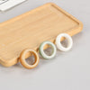 Three wooden running ring beads in yellow, green, and white on a bamboo tray