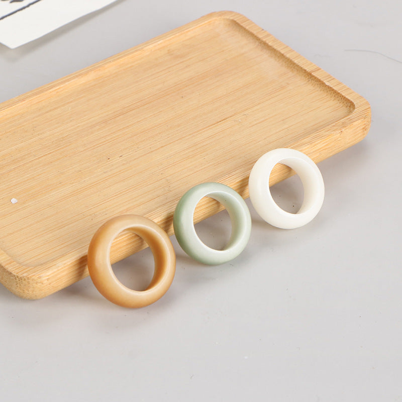 Three wooden running ring beads in yellow, green, and white on a bamboo tray