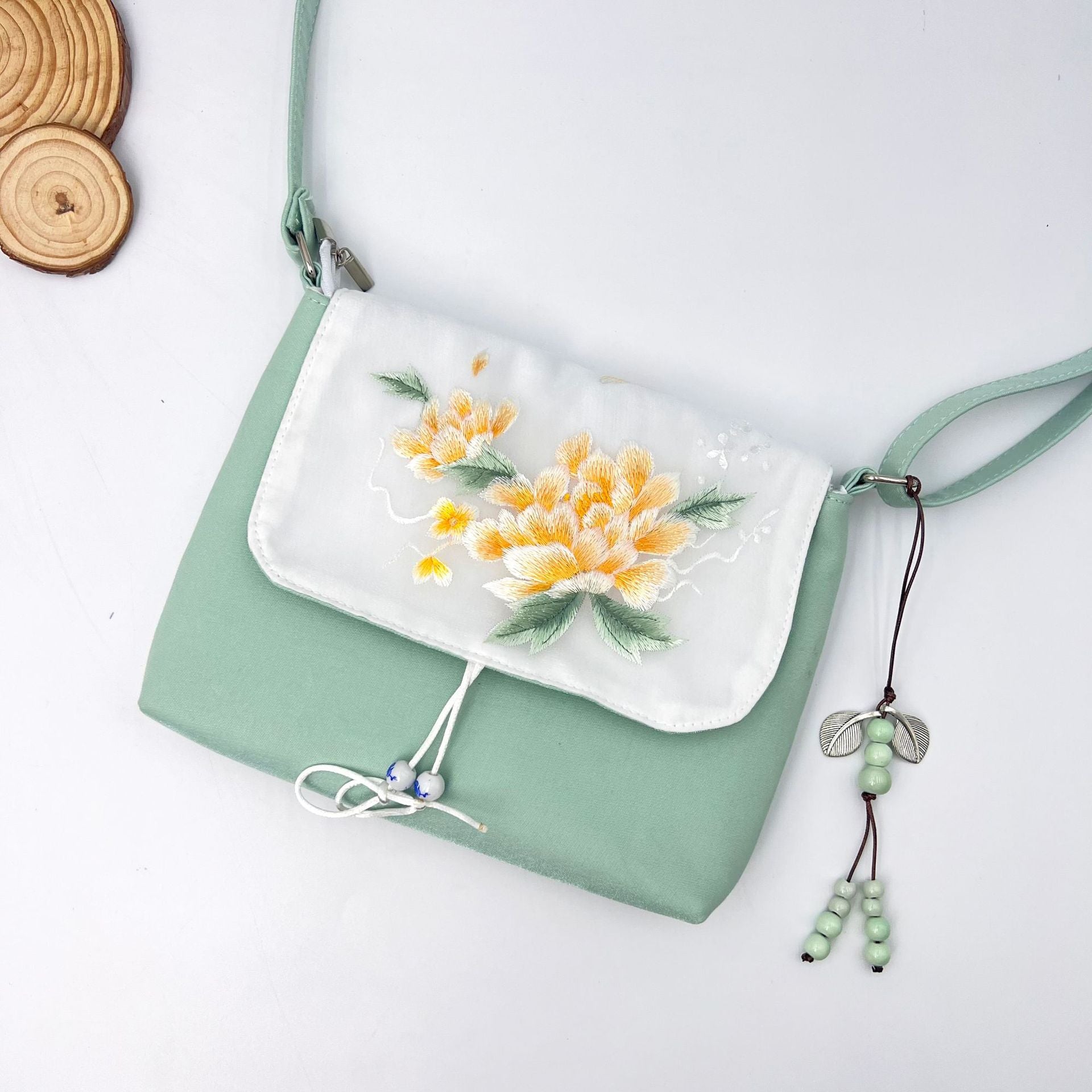Light green cotton linen crossbody bag with yellow flower embroidery on the flap