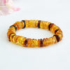 Close up view of an amber bead bracelet with a peace buckle charm